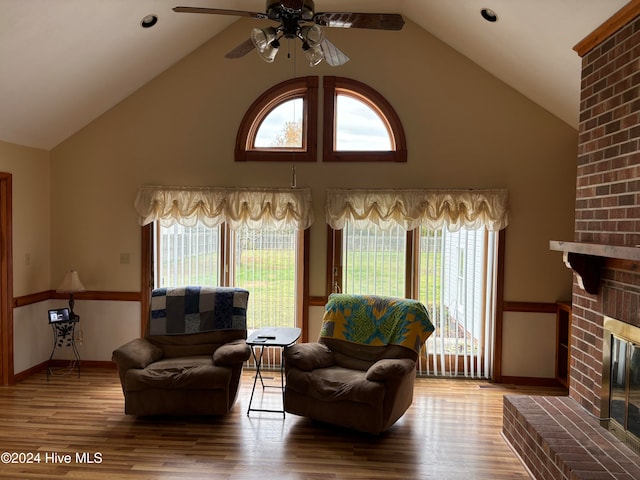 sitting room with hardwood / wood-style floors, ceiling fan, a healthy amount of sunlight, and a brick fireplace