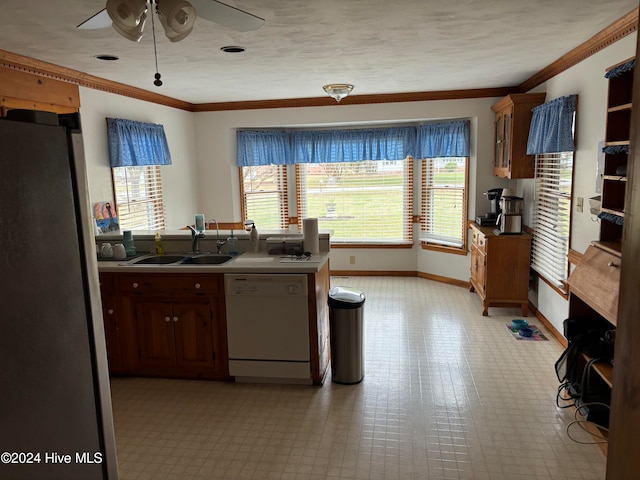 kitchen featuring white dishwasher, stainless steel refrigerator, plenty of natural light, and sink