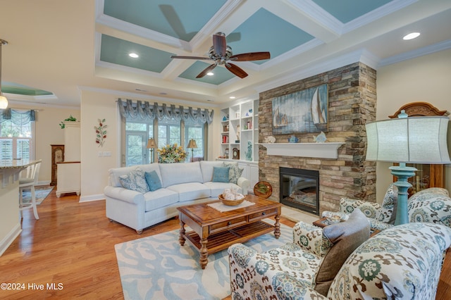 living room with a fireplace, a wealth of natural light, crown molding, and light wood-type flooring