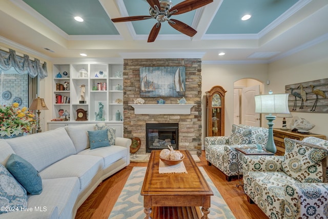 living room featuring a fireplace, ceiling fan, light wood-type flooring, and ornamental molding