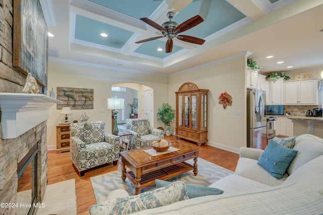 living room featuring ornamental molding, coffered ceiling, ceiling fan, light hardwood / wood-style flooring, and a fireplace