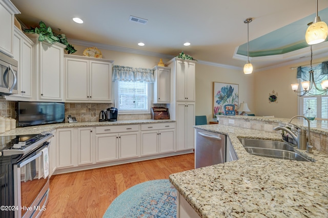 kitchen featuring white cabinets, appliances with stainless steel finishes, and hanging light fixtures