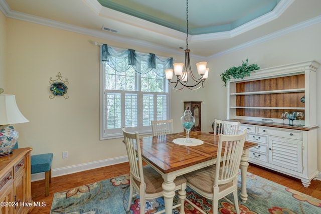 dining room featuring a tray ceiling, crown molding, dark hardwood / wood-style flooring, and a chandelier