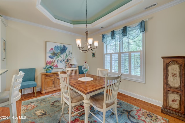 dining room featuring hardwood / wood-style flooring, a chandelier, ornamental molding, and a tray ceiling