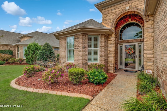 view of exterior entry with a yard