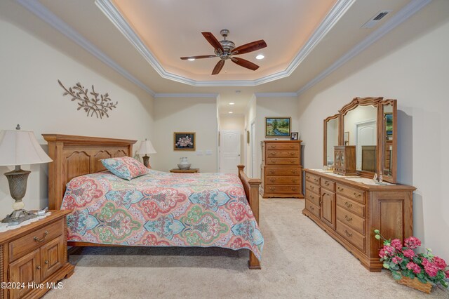 carpeted bedroom with a tray ceiling, ceiling fan, and crown molding