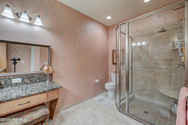 bathroom featuring vanity, toilet, and a shower with shower door