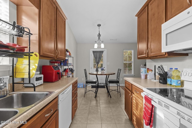 kitchen featuring sink, light tile patterned floors, decorative light fixtures, and white appliances