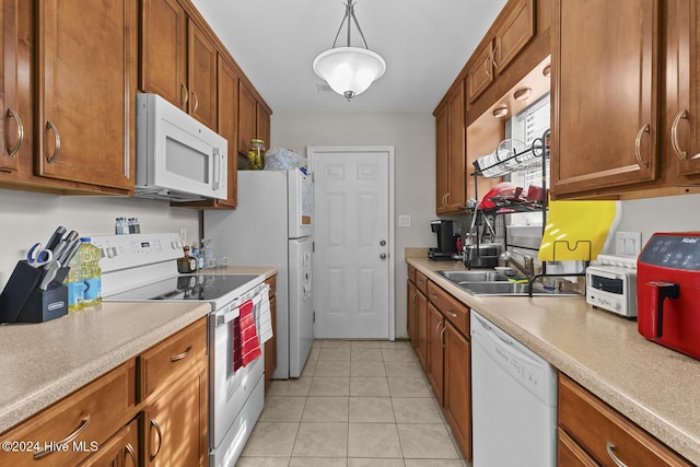 kitchen with light tile patterned floors, white appliances, hanging light fixtures, and sink