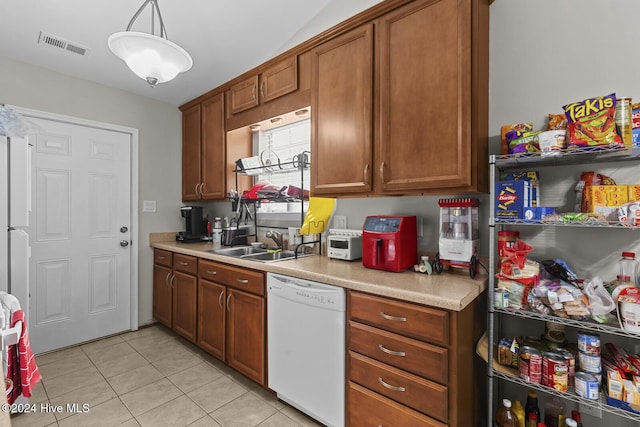 kitchen featuring white dishwasher, decorative light fixtures, light tile patterned floors, and sink