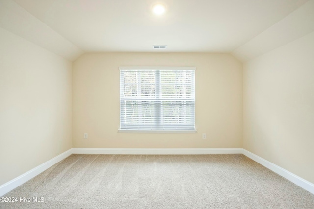 spare room featuring carpet flooring and vaulted ceiling