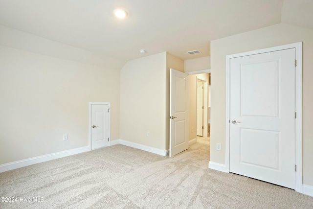 unfurnished room featuring light carpet and lofted ceiling