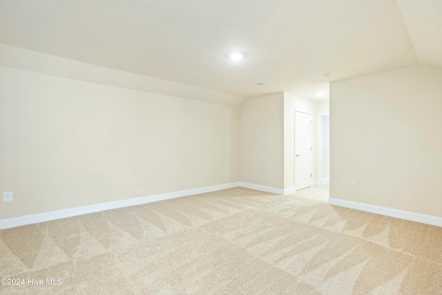 unfurnished room featuring light carpet and vaulted ceiling