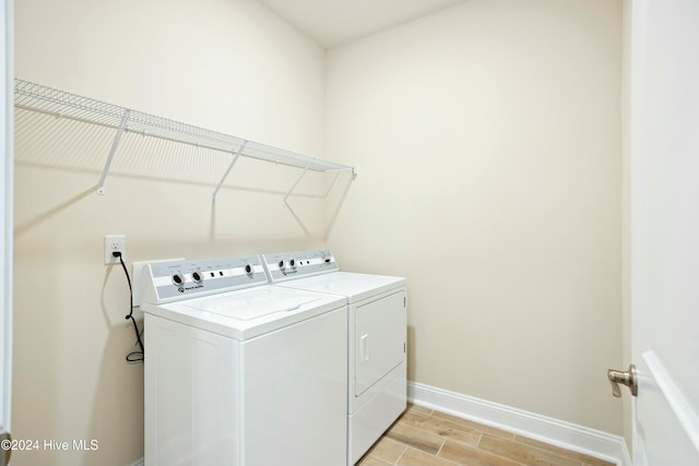 laundry room featuring independent washer and dryer and light hardwood / wood-style floors