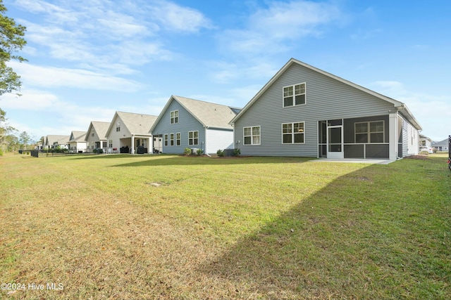 rear view of property featuring a sunroom and a lawn