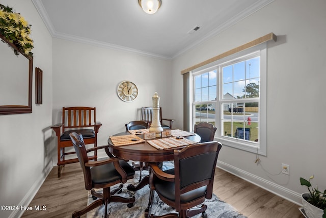 dining room with hardwood / wood-style flooring and crown molding