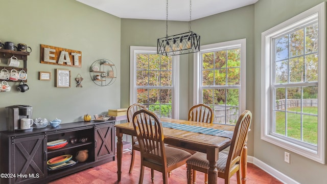 dining room featuring hardwood / wood-style flooring, a notable chandelier, a wealth of natural light, and vaulted ceiling