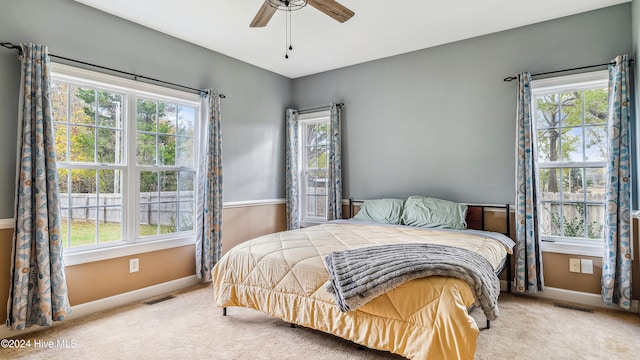 carpeted bedroom with multiple windows and ceiling fan