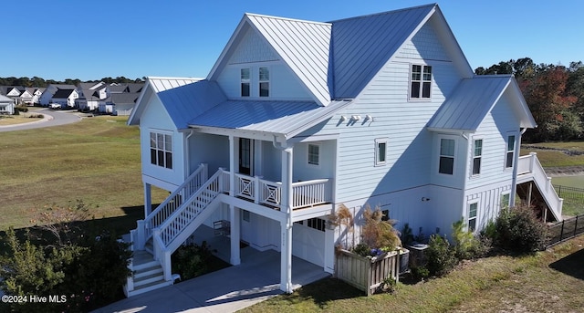 rear view of property featuring covered porch, a garage, and a yard