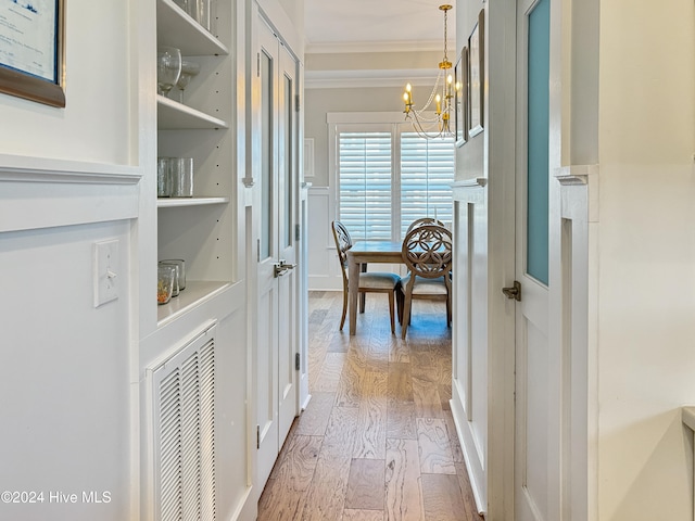 hallway featuring hardwood / wood-style floors, an inviting chandelier, and ornamental molding