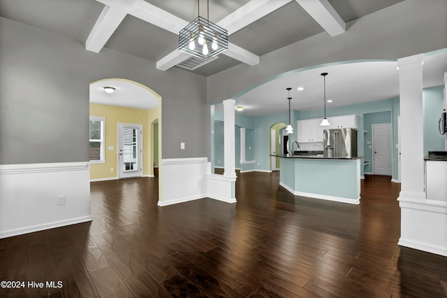 unfurnished living room with coffered ceiling, ornate columns, a notable chandelier, beam ceiling, and dark hardwood / wood-style flooring