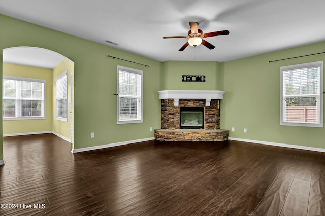 unfurnished living room with a fireplace, dark hardwood / wood-style flooring, a wealth of natural light, and ceiling fan