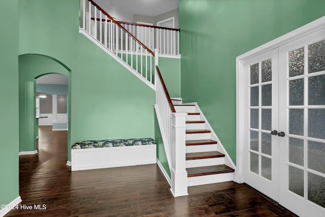 stairs with wood-type flooring, a high ceiling, and french doors