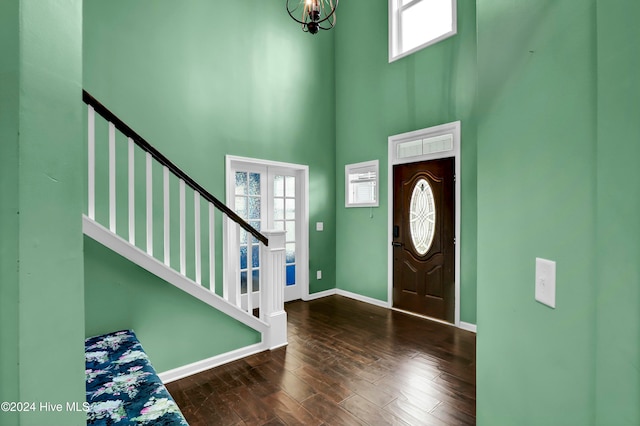 entryway with dark hardwood / wood-style flooring, a towering ceiling, and a chandelier