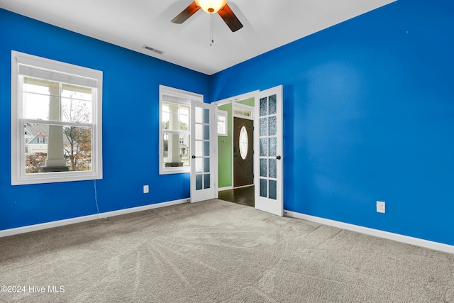 carpeted spare room with ceiling fan and french doors