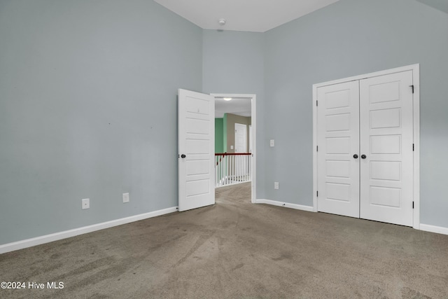 unfurnished bedroom featuring carpet, high vaulted ceiling, and a closet