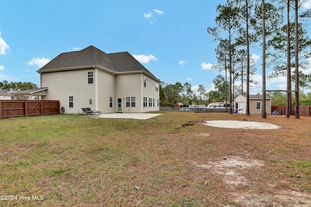 back of house featuring a lawn, a patio area, and a shed