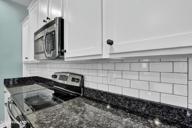 kitchen featuring appliances with stainless steel finishes, white cabinetry, and dark stone countertops