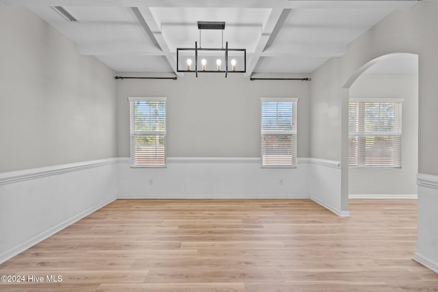 unfurnished room featuring beam ceiling, a wealth of natural light, and light hardwood / wood-style flooring