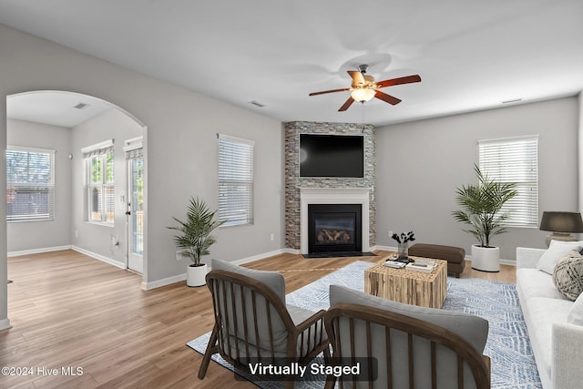 living room with a fireplace, light wood-type flooring, plenty of natural light, and ceiling fan