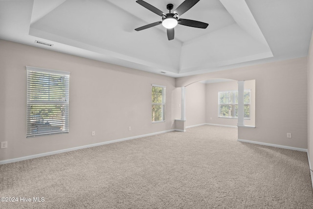 carpeted empty room featuring ceiling fan, a healthy amount of sunlight, and a raised ceiling