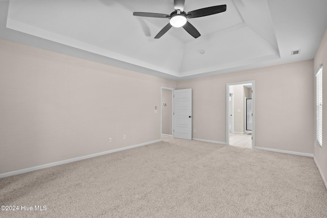 carpeted spare room featuring a tray ceiling, ceiling fan, and plenty of natural light