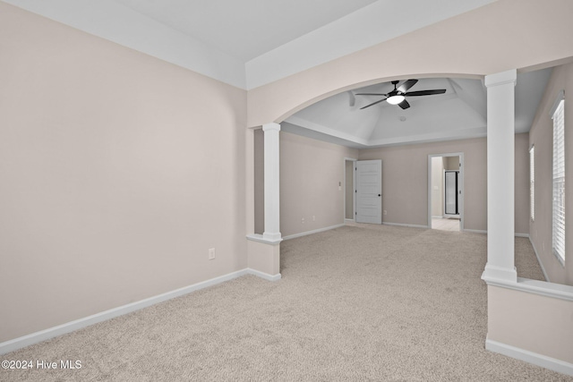 empty room with light carpet, decorative columns, a raised ceiling, and ceiling fan