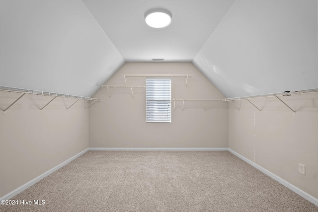 walk in closet with carpet floors and vaulted ceiling