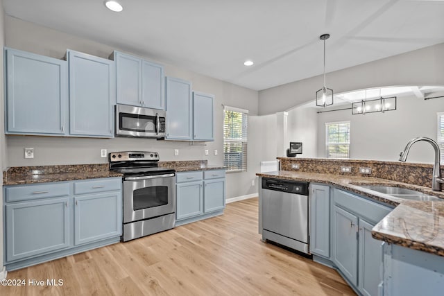 kitchen featuring blue cabinetry, a healthy amount of sunlight, hanging light fixtures, and appliances with stainless steel finishes