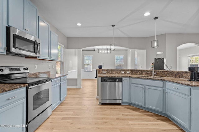 kitchen featuring blue cabinetry, sink, hanging light fixtures, light hardwood / wood-style flooring, and appliances with stainless steel finishes