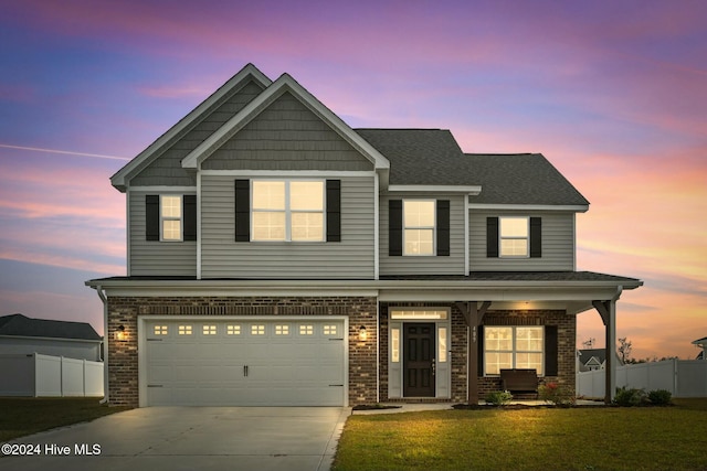 craftsman-style home with concrete driveway, brick siding, a lawn, and fence