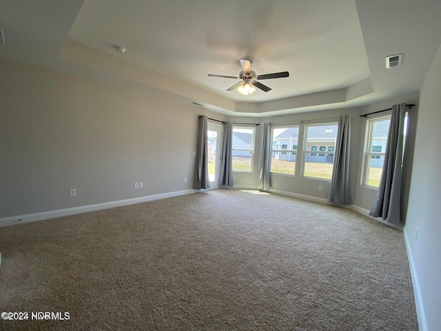 spare room with carpet floors, a tray ceiling, and ceiling fan