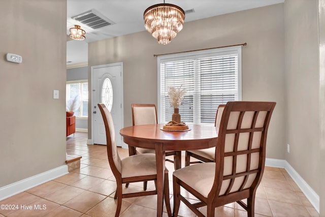 tiled dining area featuring plenty of natural light and an inviting chandelier