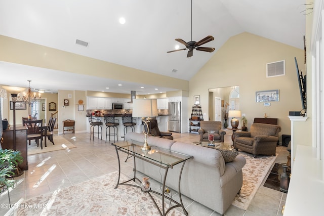 tiled living room with high vaulted ceiling and ceiling fan with notable chandelier