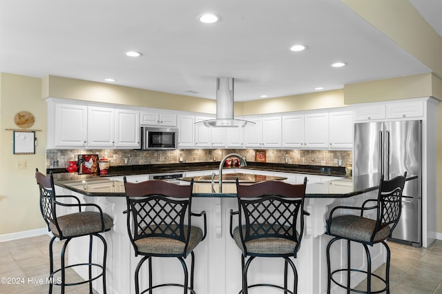 kitchen with white cabinetry, a kitchen breakfast bar, island exhaust hood, a kitchen island with sink, and appliances with stainless steel finishes