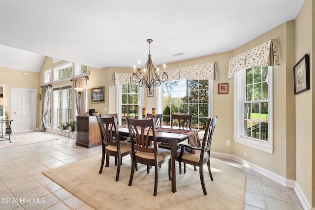 tiled dining room featuring an inviting chandelier and lofted ceiling