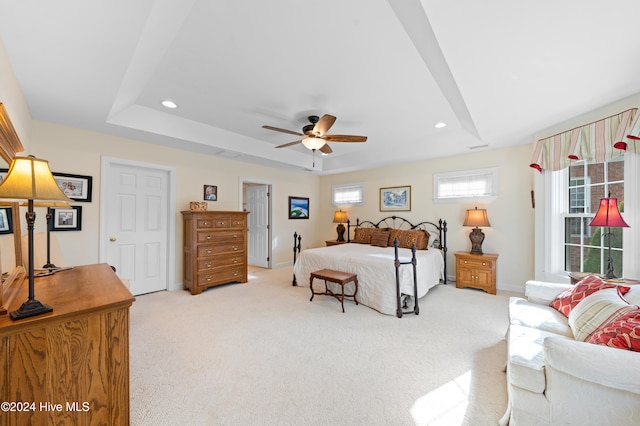 carpeted bedroom with ceiling fan and a tray ceiling