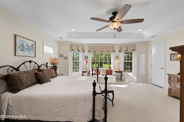 carpeted bedroom with a raised ceiling and ceiling fan