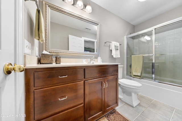 full bathroom featuring toilet, vanity, tile patterned floors, and enclosed tub / shower combo