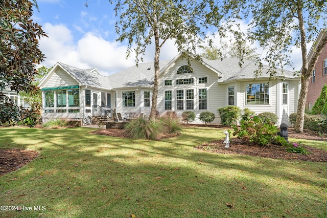 back of property with a sunroom and a yard